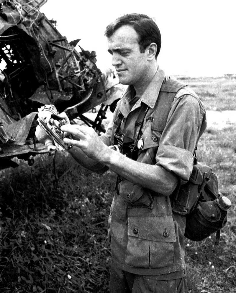 Arnett stands beside wreckage of A-1 Skyraider, Bien Hoa airbase, outside Saigon, circa 1965